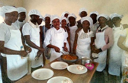 Charity Mweene (holding the pan) is teaching 25
sponsored students the art of catering